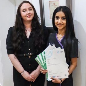 office manager standing next to a student that's holding her certificates