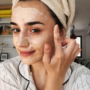 selfie of woman applying a face mask at home